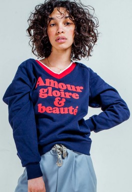 Photography. model with curly hair wears blue v neck sweatshirt. 