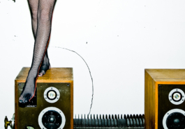 photography. Close up of legs wearing fishnet tights, standing on a big speaker. 