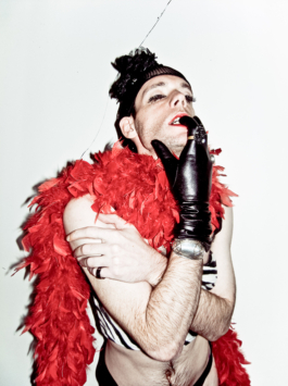 Photography. Queer with leather gloves and red boa. 