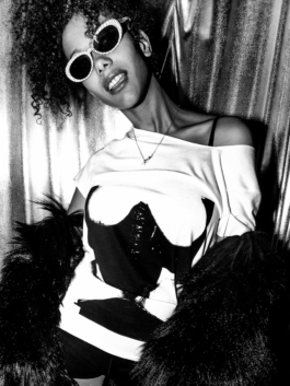 Photography. Model posing with printed t-shirt an furs jacket in front of a shiny curtain . Night-club. 